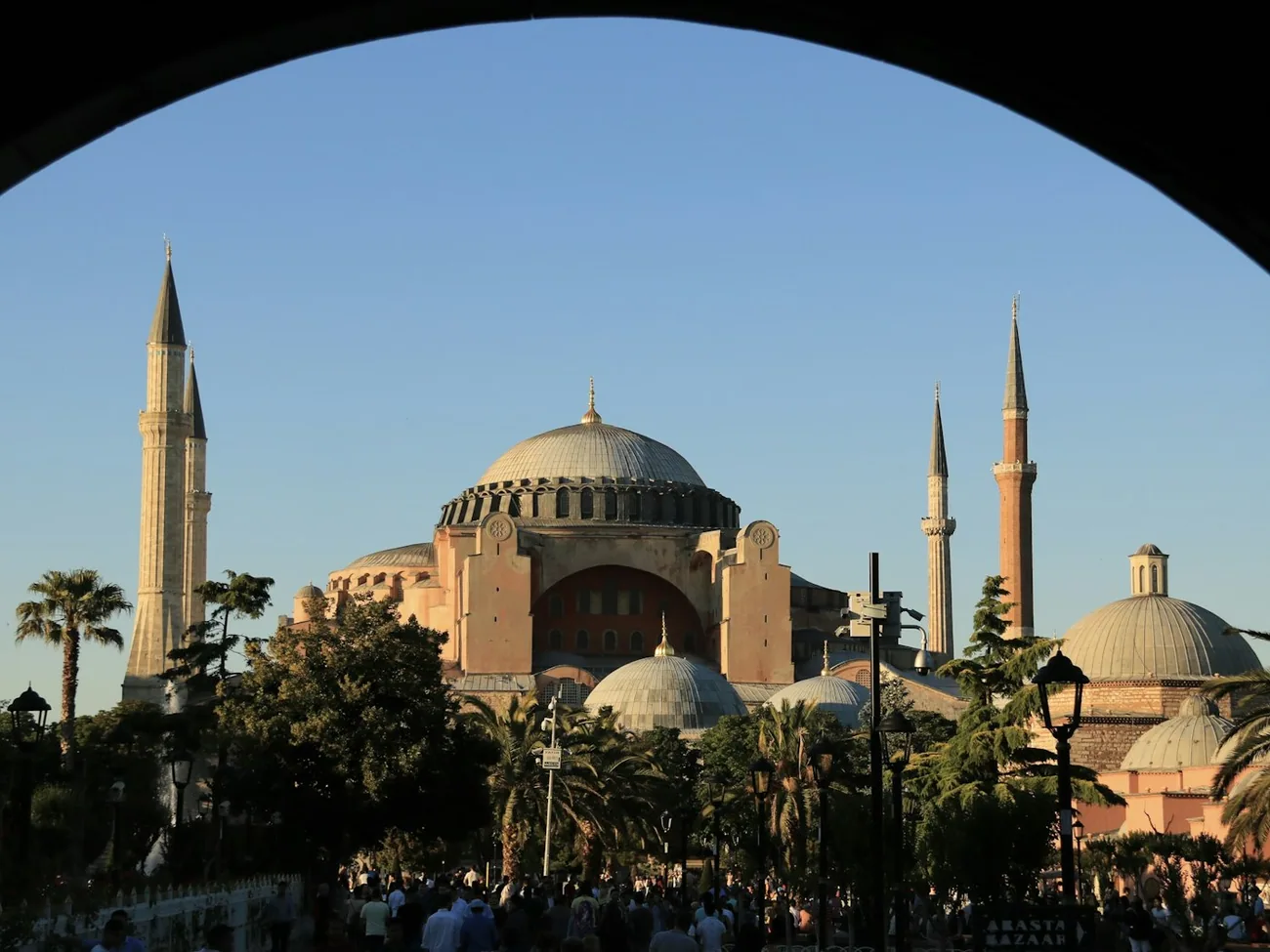 Hagia Sofia i Istanbul sett gjennom en steinbue, med palmer og folk på plassen utenfor