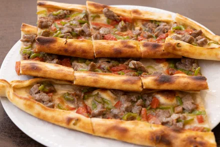 Avlange båtformede pide med kjøtt og paprika på et fat
