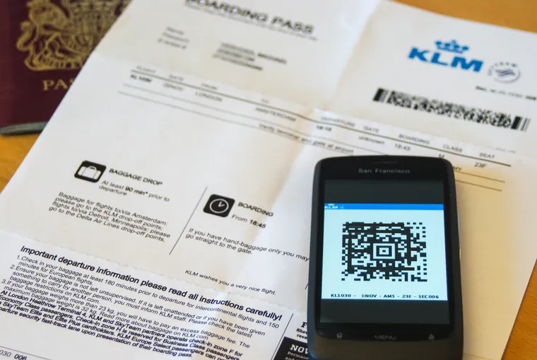 Reisedokumenter og en mobil med QR-kode på en skranke